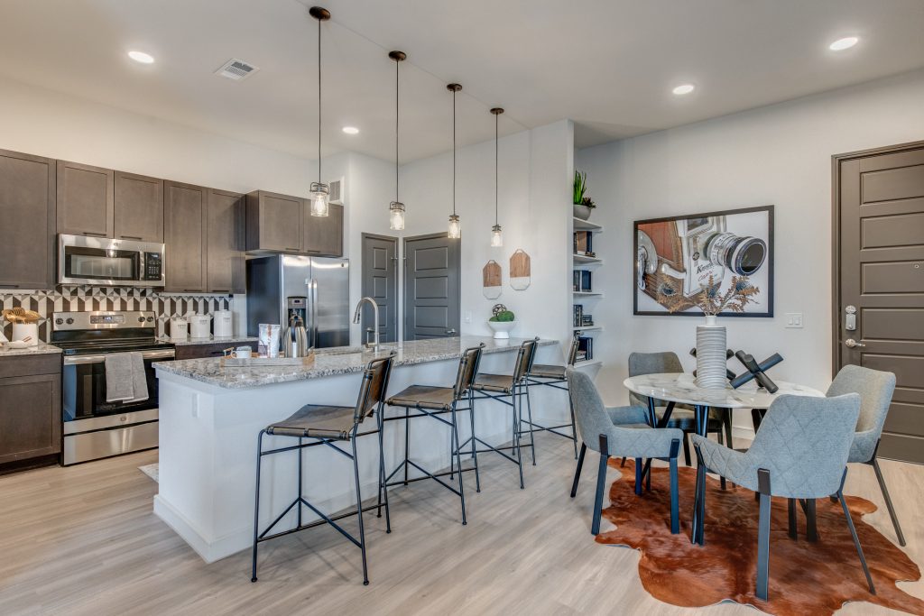 Kitchen area with stainless steel appliances, granite tops, single sink, island, bar seating and table seating