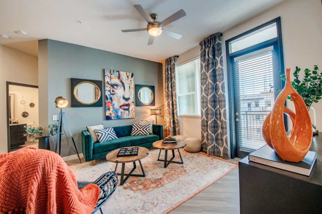 Living room area with outdoor patio access, wood style flooring, couch and chair seating, and wall paintings