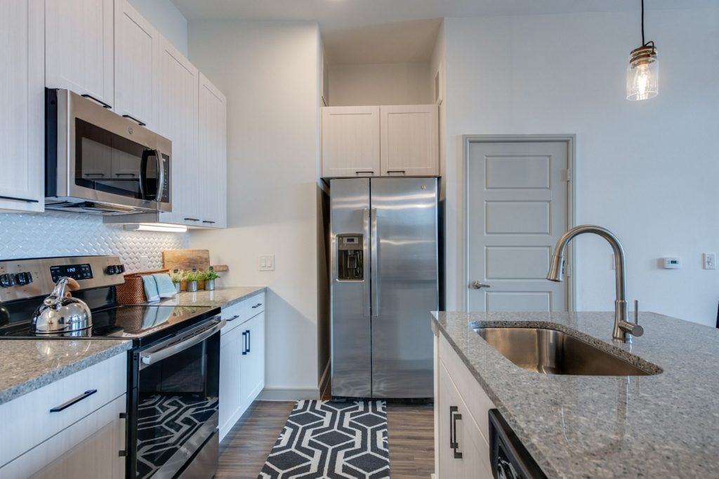 Kitchen area with stainless steel appliances, granite tops, single sink, and island