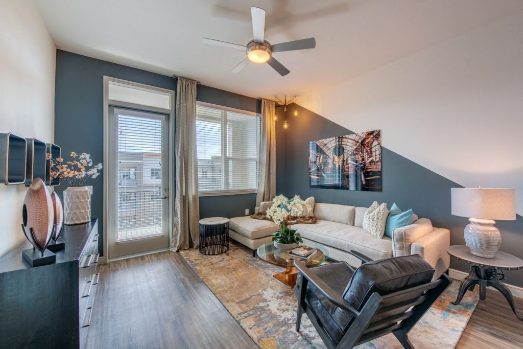 Living room area with outdoor patio access, wood style flooring, couch and chair seating, and wall paintings