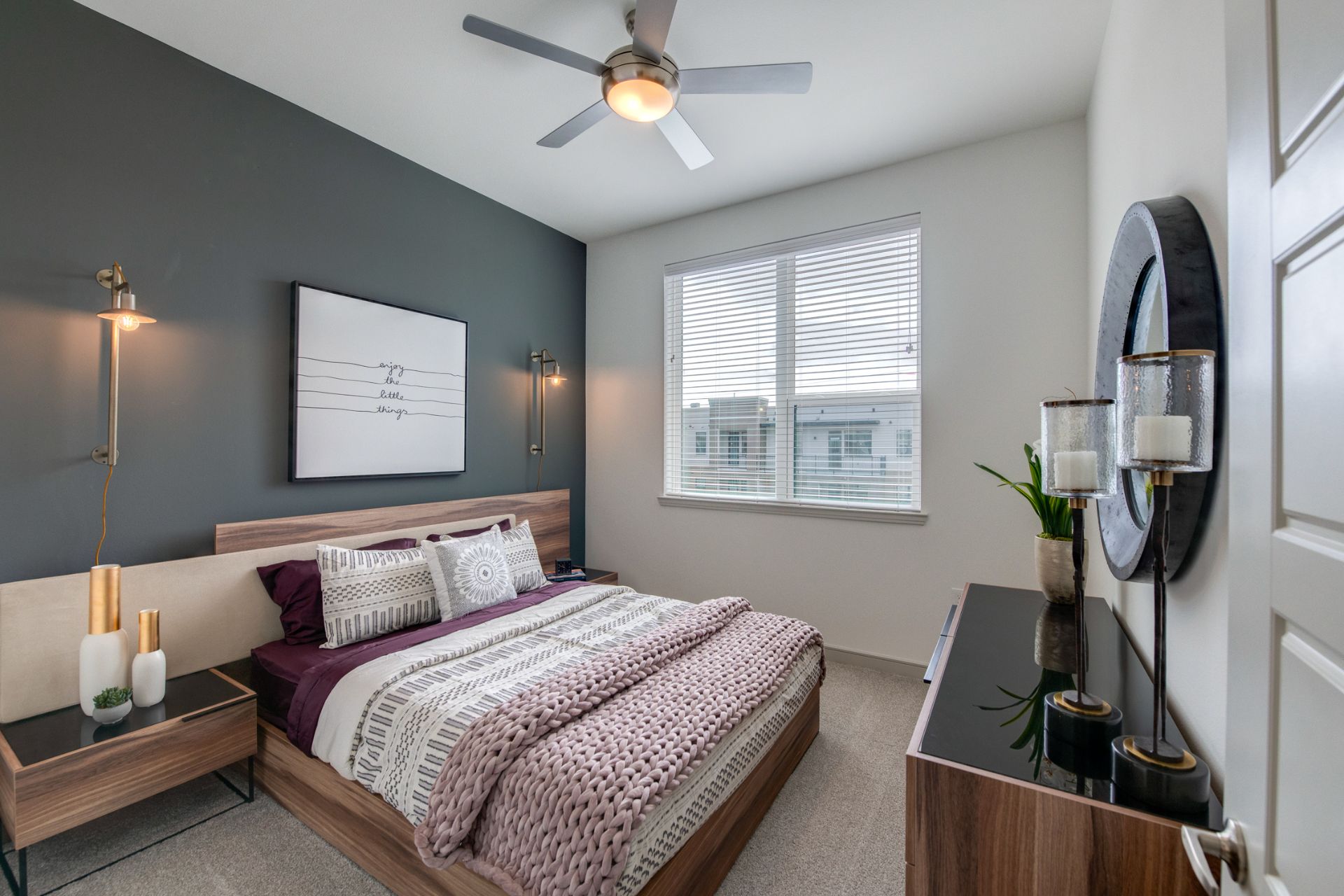 Bedroom area with carpet flooring, mirror, wall artwork, ceiling fan, and warm lighting