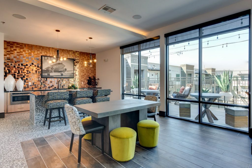 Clubhouse kitchen lounge with single sink, island, bar seating, table seating, lounge seating, and floor to ceiling windows