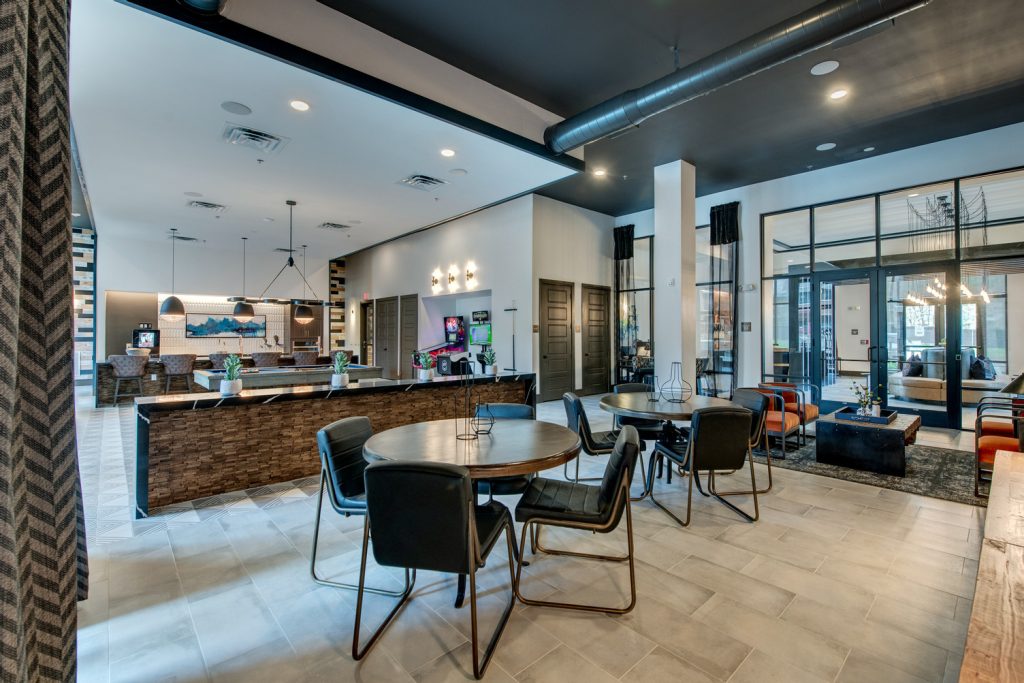 Clubhouse lounging area with table and lounge seating, tile flooring, television, and modern decor