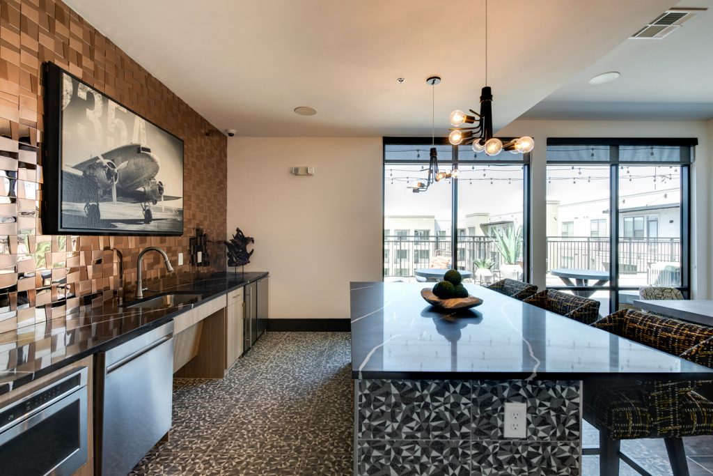 Clubhouse kitchen lounge with single sink, island, bar seating, and floor to ceiling windows