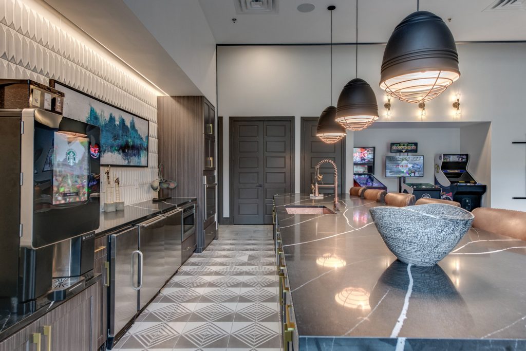 Clubhouse kitchen with stainless steel appliances, single sink, island, and bar seating