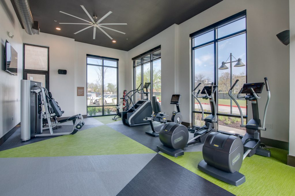 Indoor gym area with workout machines, weights, floor to ceiling windows, and ceiling fans