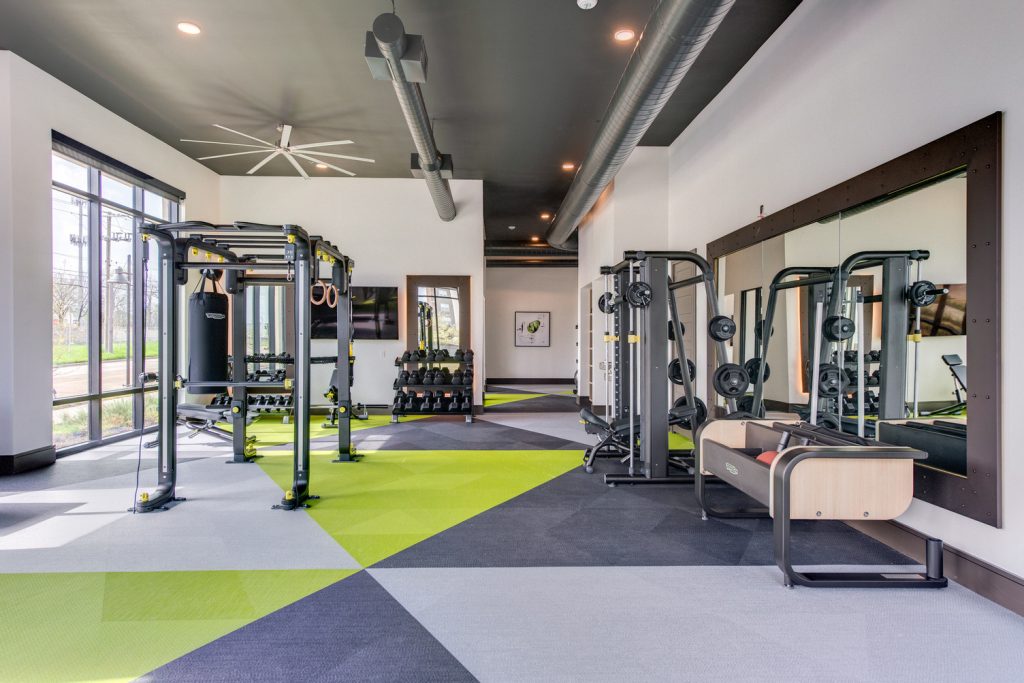 Indoor gym area with workout machines, weights, floor to ceiling windows, television, and ceiling fans