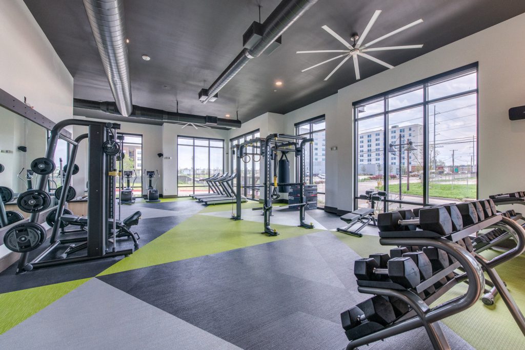 Indoor gym area with workout machines, weights, floor to ceiling windows, and ceiling fans