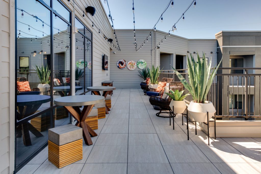 Alt view of Patio on Rooftop with string lights, seating, and various planters, as well as wall art