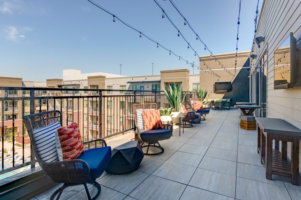 Rooftop patio with stringlights, seating, planters, and various other things and chairs