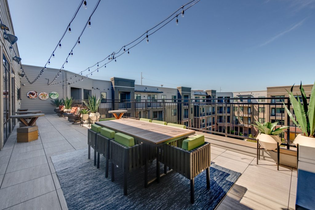 Rooftop patio with stringlights, seating, planters, and various other things