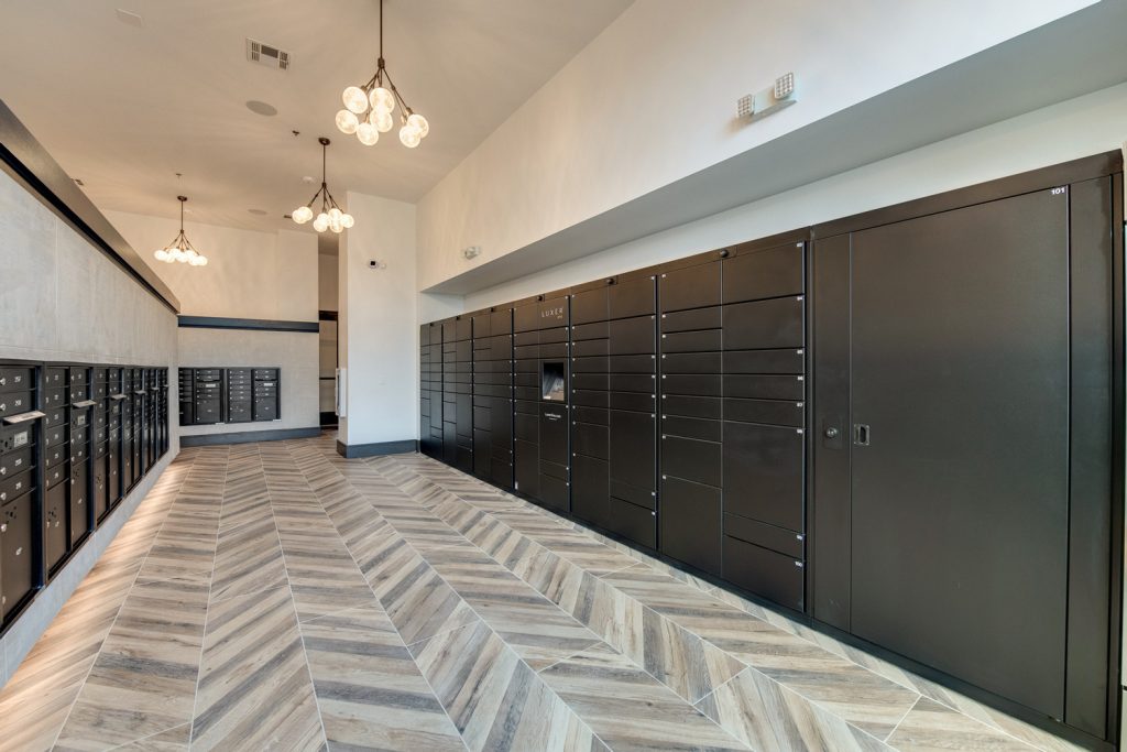 Mail delivery room with wood style flooring and low hanging lights