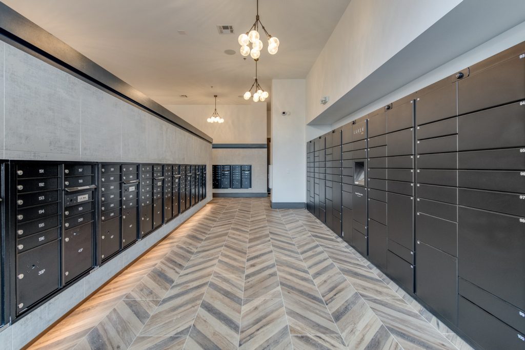 Mail delivery room with wood style flooring and low hanging lights